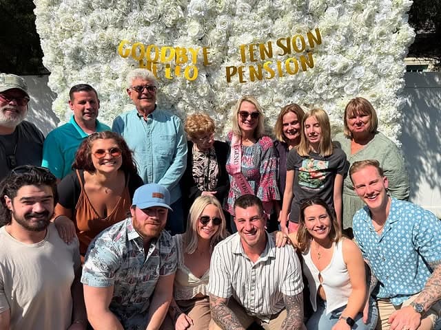 Retirement party group photo in front of a flower wall